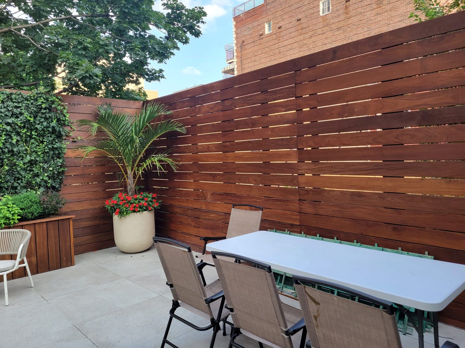 Brownstone backyard with horizontal IPE wood fence and a dining setup at twilight