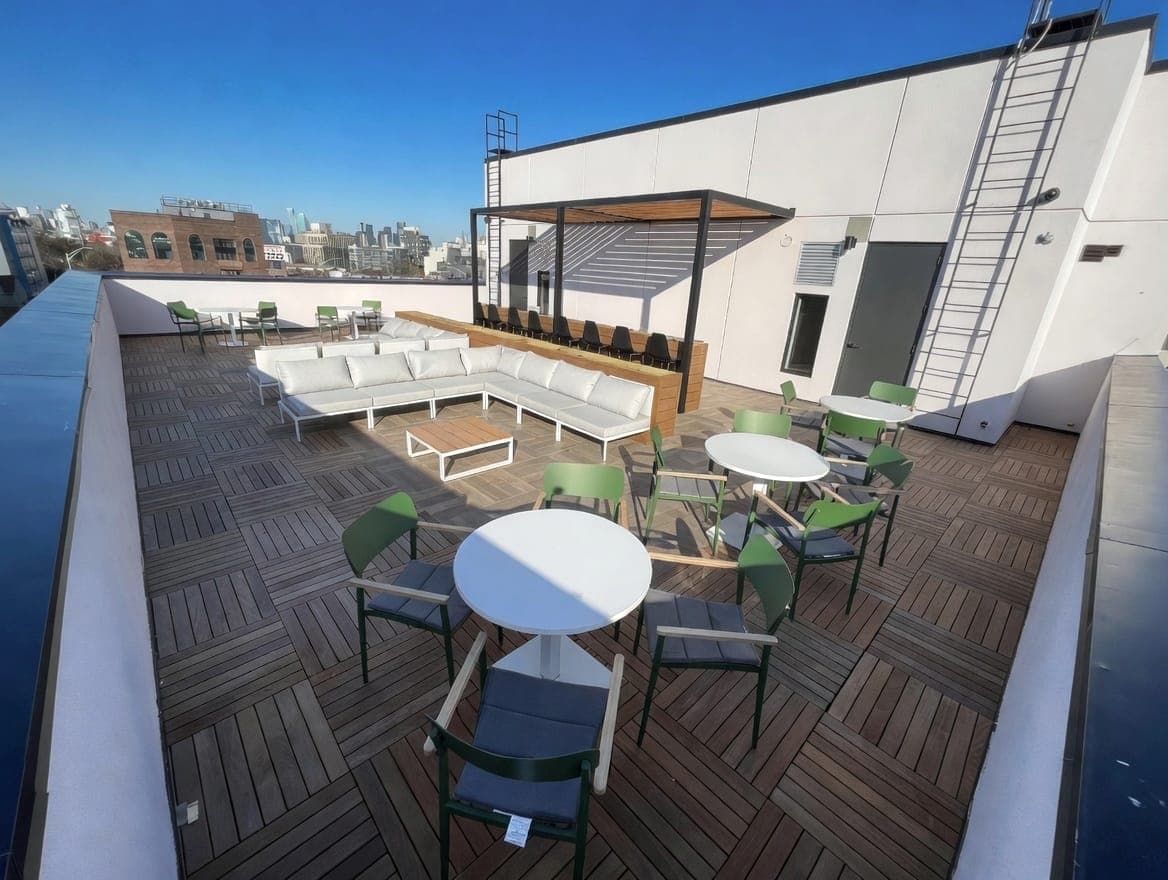 Rooftop terrace with white sectional seating, low pergola, and skyline view